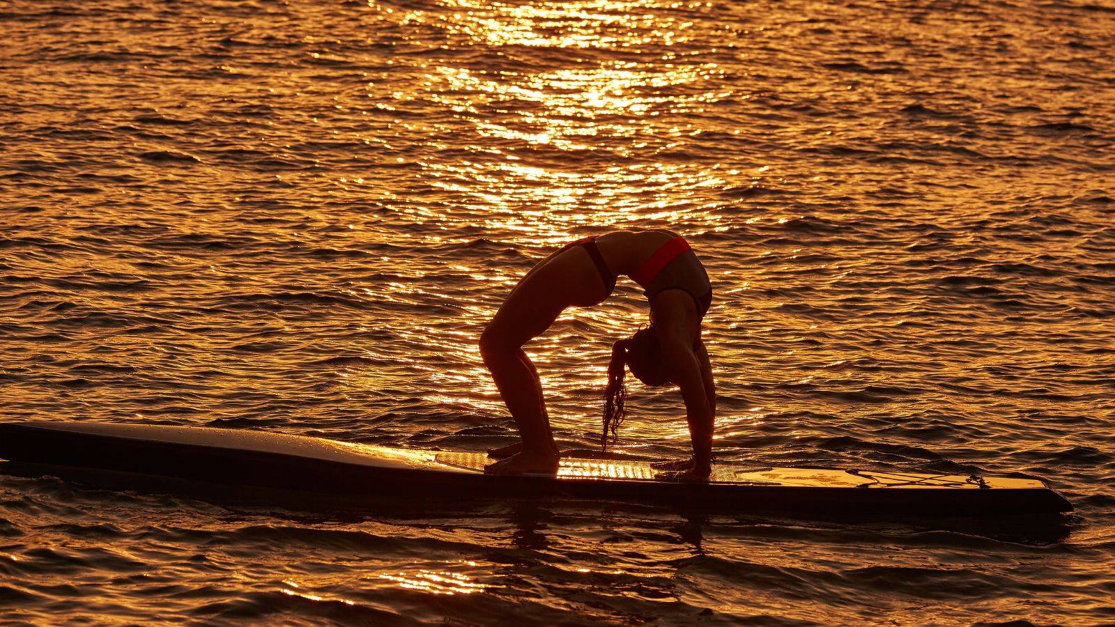 femme effectuant une pose yoga sur un surf